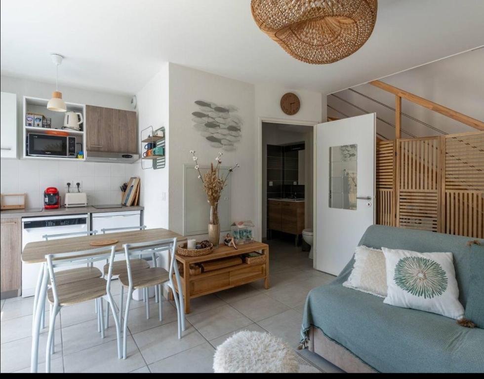 un salon avec une table et un canapé bleu dans l'établissement Maison fonctionnelle et bien située, à Mimizan