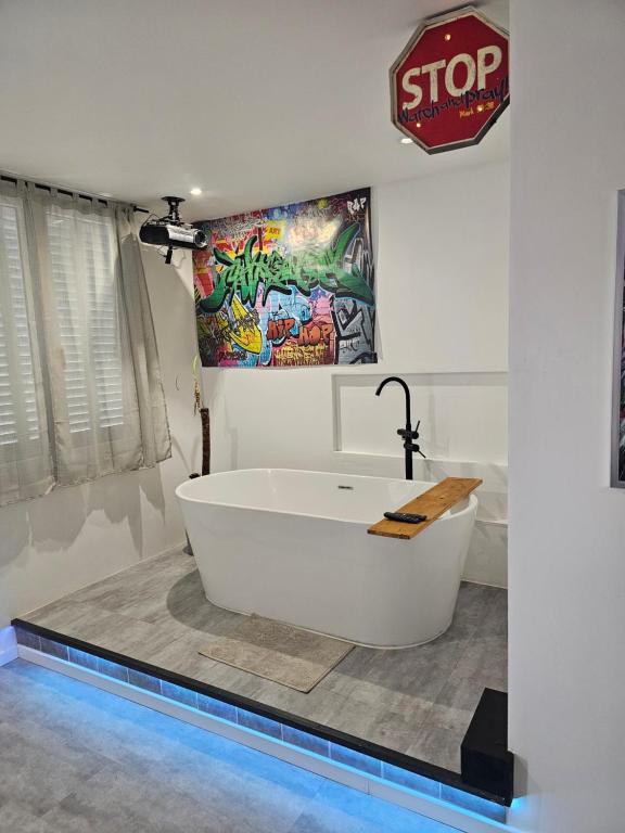 a bath tub in a bathroom with a painting on the wall at 1988 NEW YORK Baignoire ilot et video projecteur in Seyssinet-Pariset