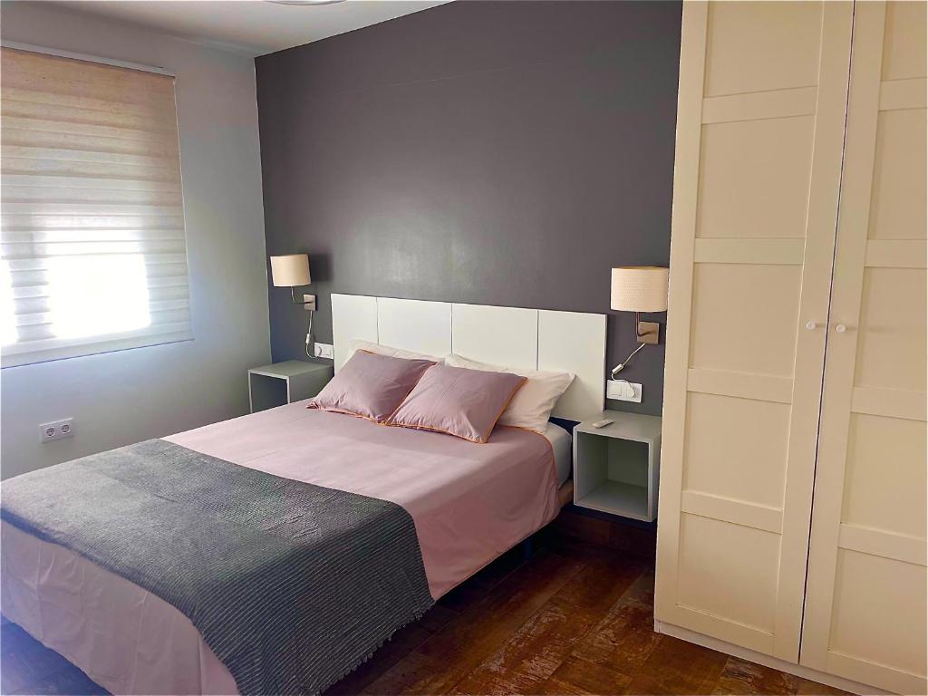 sypialnia z dużym łóżkiem z 2 różowymi poduszkami w obiekcie Apartamento con Piscina ADULTS ONLY w mieście Chiclana de la Frontera