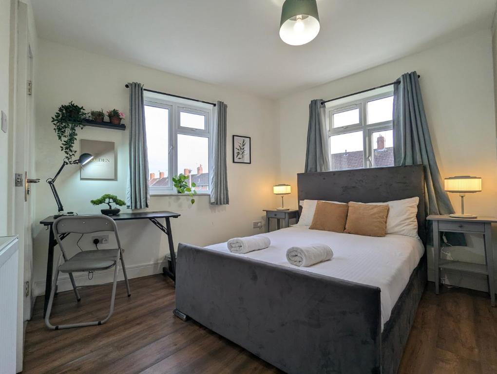 a bedroom with a bed and a desk and two windows at 2 Ensuite Bedroom House Near Centre Free Parking in York