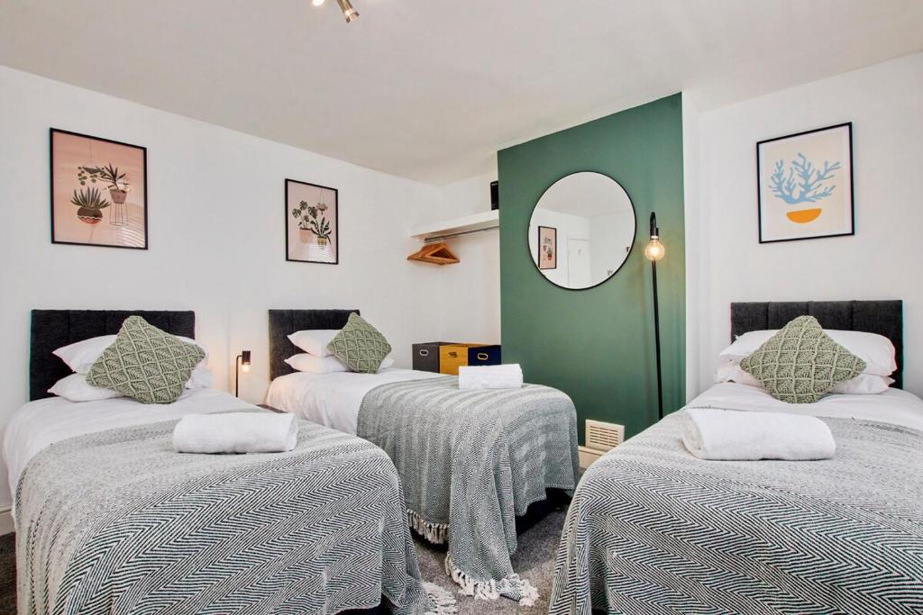 a room with three beds and a mirror at Charming House - Close to City Centre - Self-Check-In - Free Parking, Fast WiFi, Smart TV and Garden by Yoko Property in Sheffield