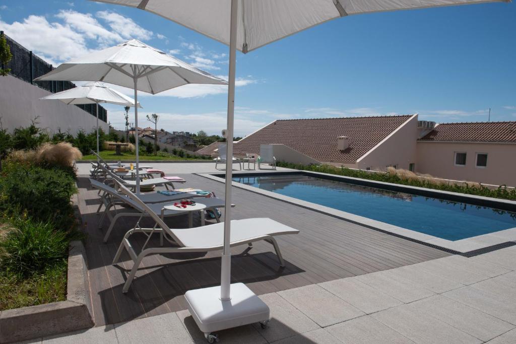 a patio with tables and umbrellas next to a pool at Vila Marta - Toutinegra in Vila Franca do Campo