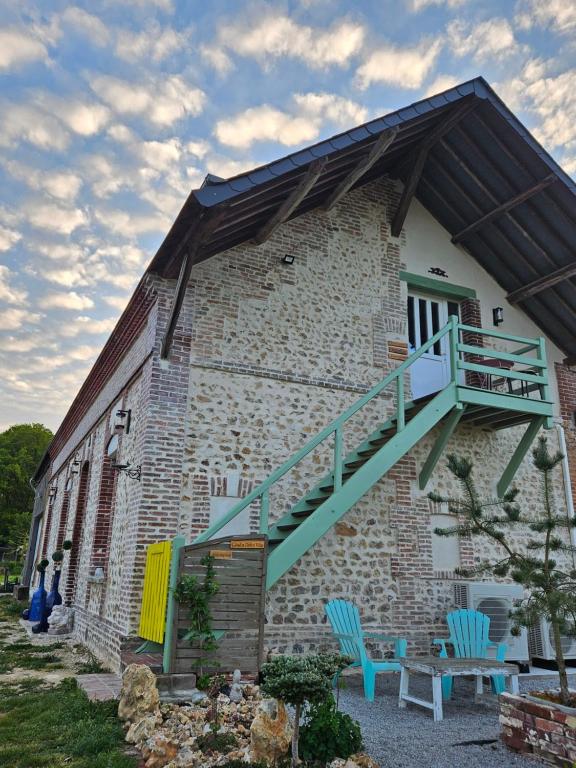 a brick building with blue chairs and a staircase at Domaine de la Dolce Vita de Gaudreville la rivière in Gaudreville-la-Rivière