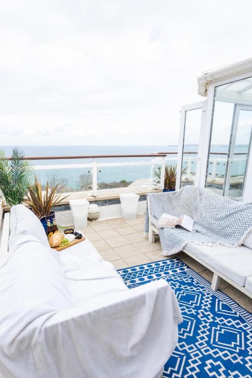 a balcony with white furniture and a view of the ocean at NEW! Stunning 2 Bed Beach Front Penthouse Apartment - Topaz, Compass Point in Carbis Bay