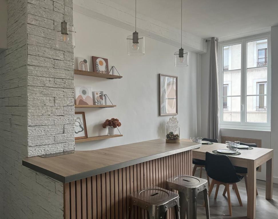 une cuisine avec un comptoir, une table et des chaises dans l'établissement Les Carmes - Logement entier, appartement, Vienne - France, à Vienne