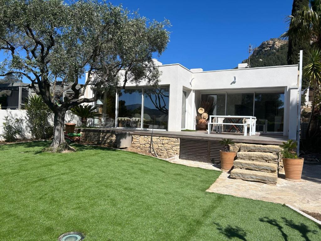 a white house with a lawn in front of it at Villa la Grande Bastide piscine et tennis collectif in Cassis