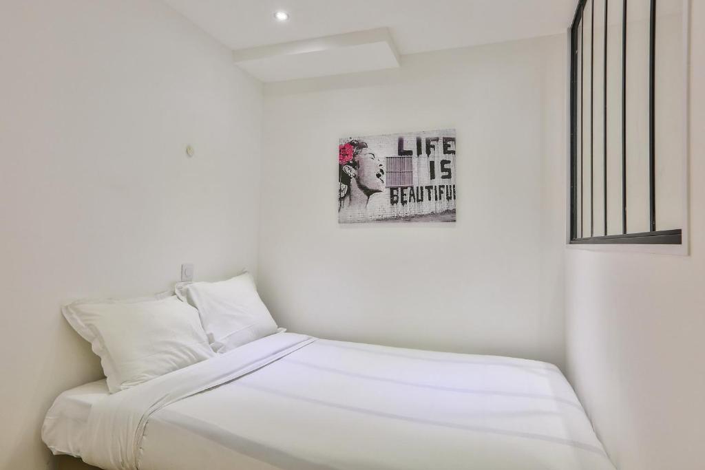 une chambre avec un lit avec un tableau sur le mur dans l'établissement Modern and peaceful apartment - 1BR 5P - Sentier, à Paris