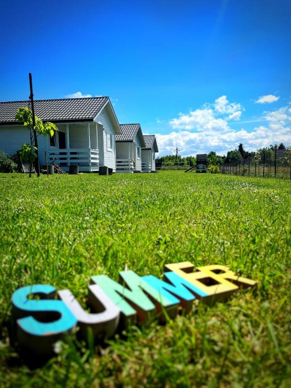 a sign in the grass in front of a house at Domki na górce in Kołczewo