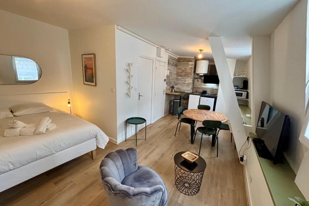 une chambre avec un lit, une table et des chaises dans l'établissement Casa Bondy - Studio - Coeur de ville de Brive, à Brive-la-Gaillarde