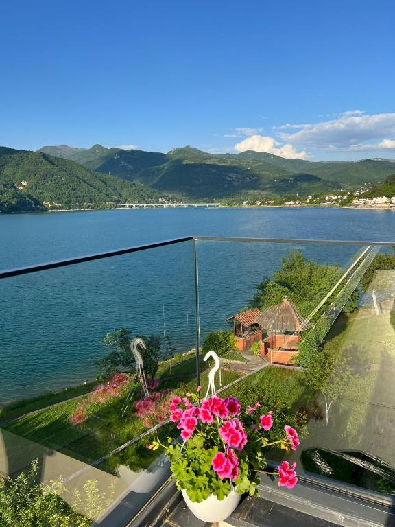 a balcony with flowers and a view of a lake at Royal Terrace Konjic in Železnička Stanica Ostrožac