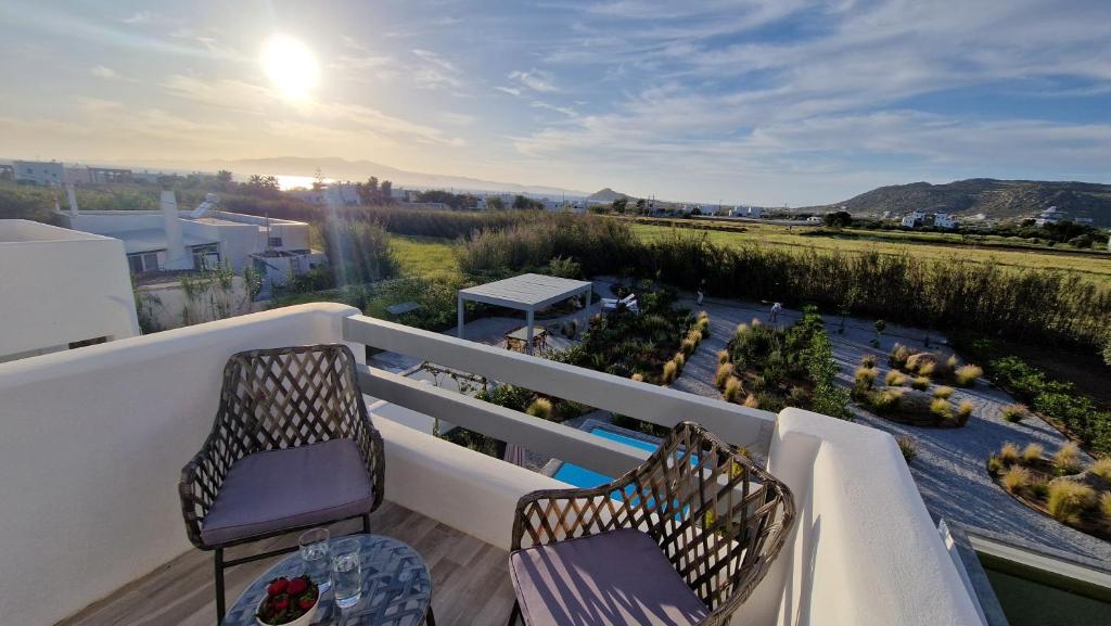 a balcony with two chairs and a view of a garden at Apartment Filotimo with sea and sunset view in Kastraki