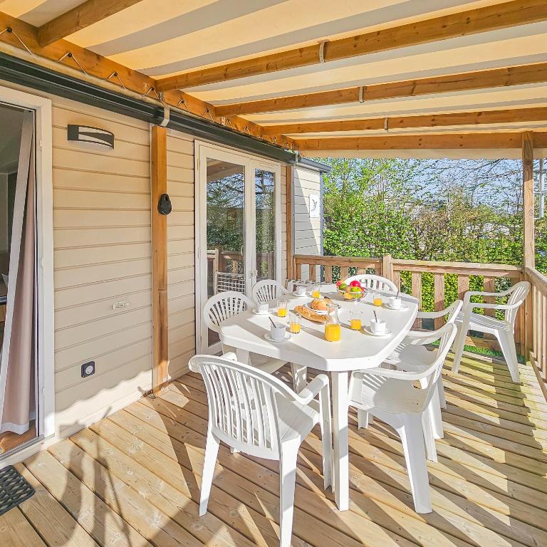une table et des chaises blanches sur une terrasse en bois dans l'établissement laly, à Litteau
