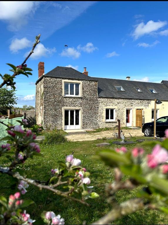 une maison en pierre dans une cour avec des fleurs au premier plan dans l'établissement Le relais de Noron, à Noron-la-Poterie