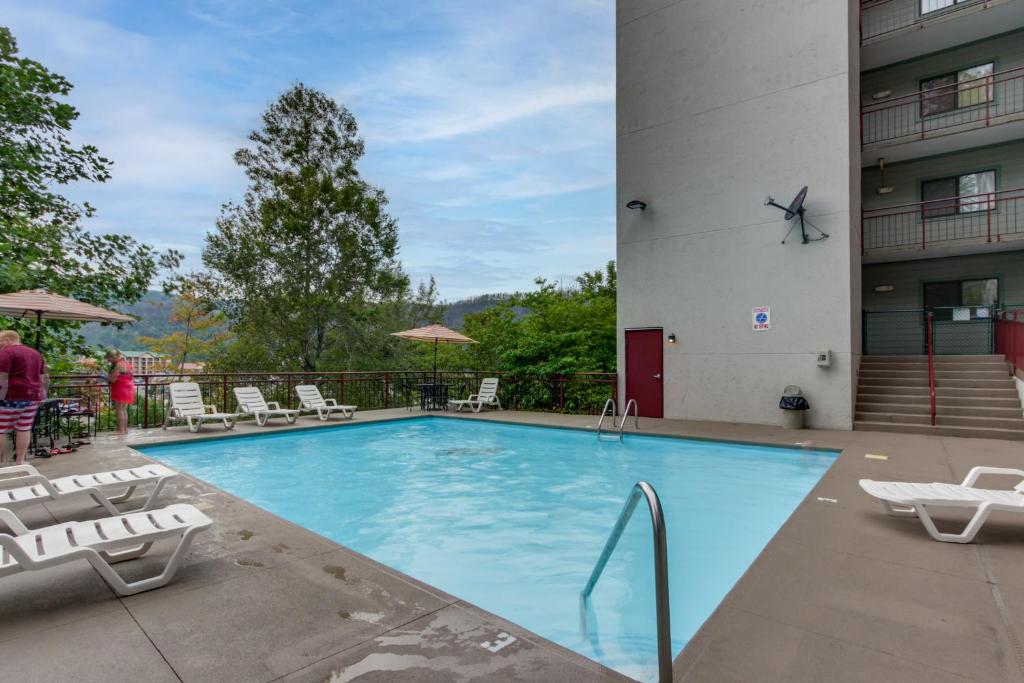 a large swimming pool with chairs and a building at Bear-Sighting Condo Walk to Downtown Gatlinburg! in Gatlinburg