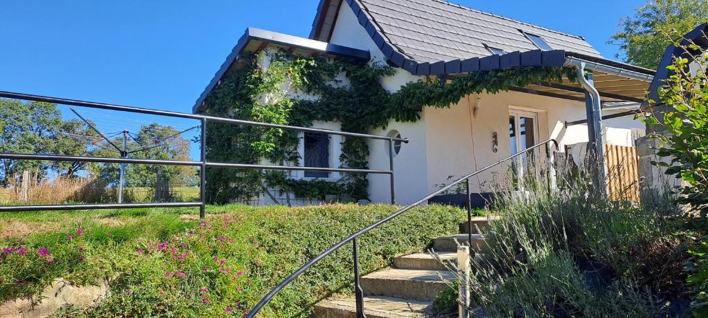 Une petite maison blanche avec des escaliers en face de celle-ci dans l'établissement Gîte 2 étoiles proche Salers Cantal Auvergne, à Besse