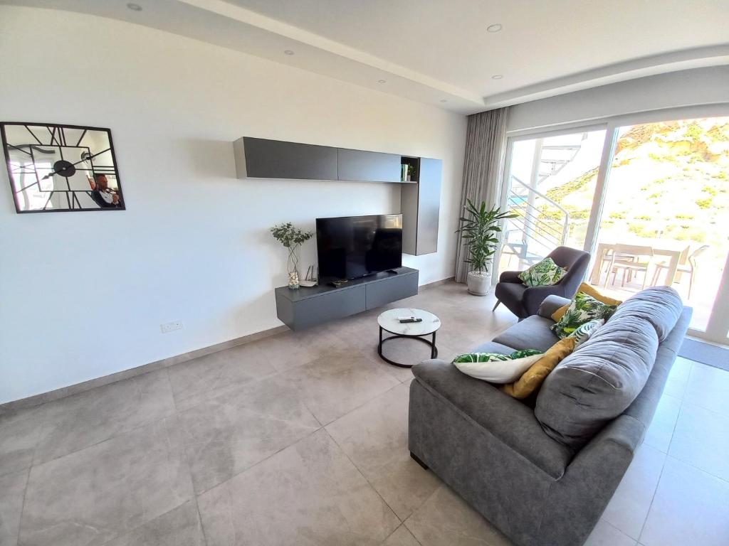 un soggiorno con un divano e una TV di Yellow Hill Penthouse a Żebbuġ