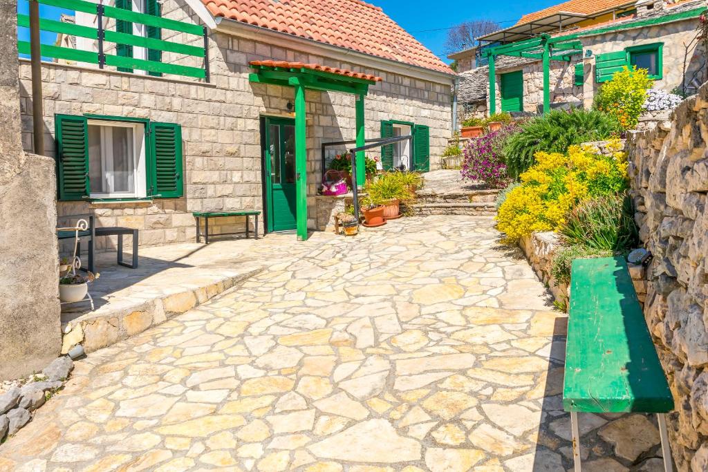a stone pathway in front of a house with a green door at House Moj mir in Primošten