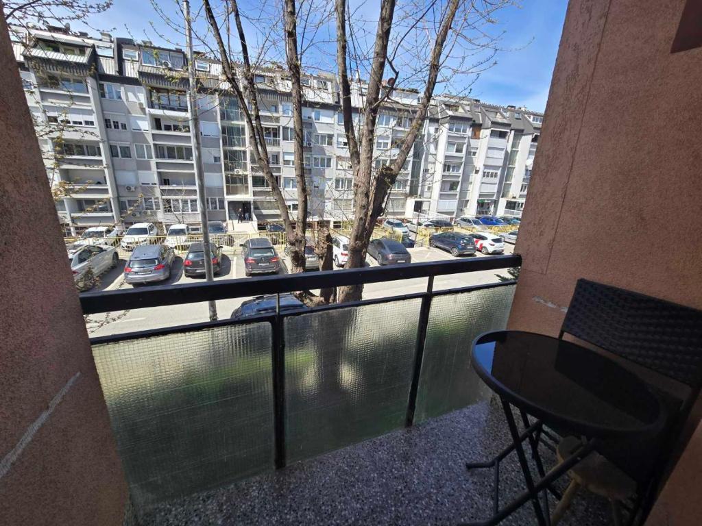 Marina G apartment في بريشتيني: شرفة بها طاولة وإطلالة على موقف سيارات
