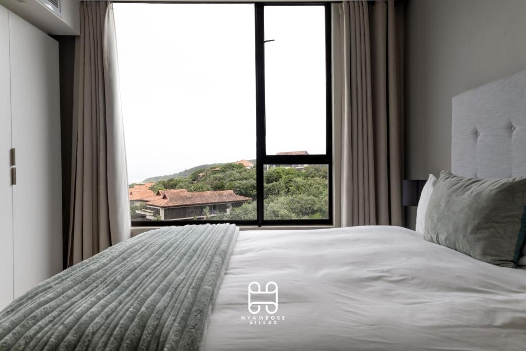 a bedroom with a bed with a large window at Zimbali Suites Ocean View Nyambose Villas in Ballito