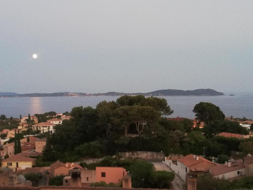 - une vue sur une ville avec la lune sur l'eau dans l'établissement Maison vue mer, à Carqueiranne