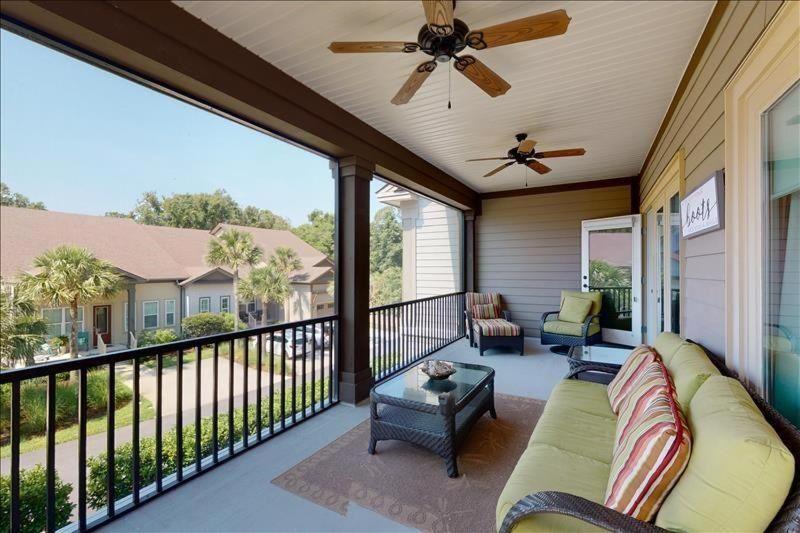 a screened in porch with a couch and a ceiling fan at Garden Cottage 10 in Jekyll Island