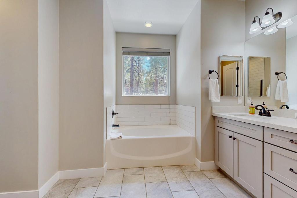 a white bathroom with a tub and a window at Pinnacle Pines in Flagstaff