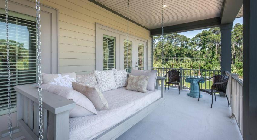 a porch with a swinging couch on a balcony at Poolside Cottage 32 in Jekyll Island