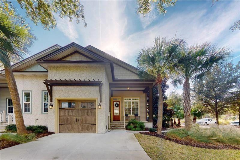 a house with palm trees in front of it at Poolside Cottage 57 in Jekyll Island