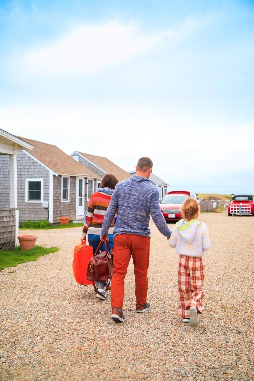 a man and two children holding hands while walking down a driveway at Truro Beach Cottages in Truro