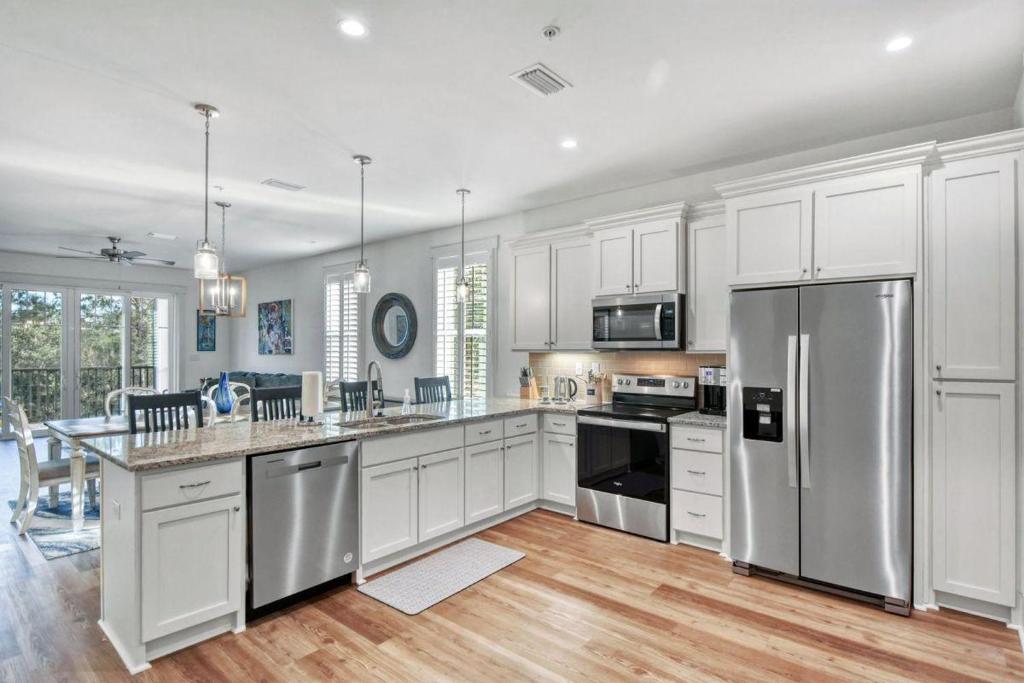 a kitchen with white cabinets and a stainless steel refrigerator at Moorings 107 in Jekyll Island