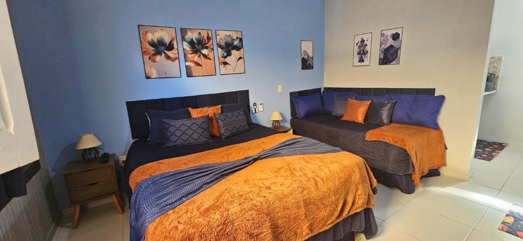 a bedroom with two beds with orange and blue at Studio Cinza em frente à praia in Aracaju