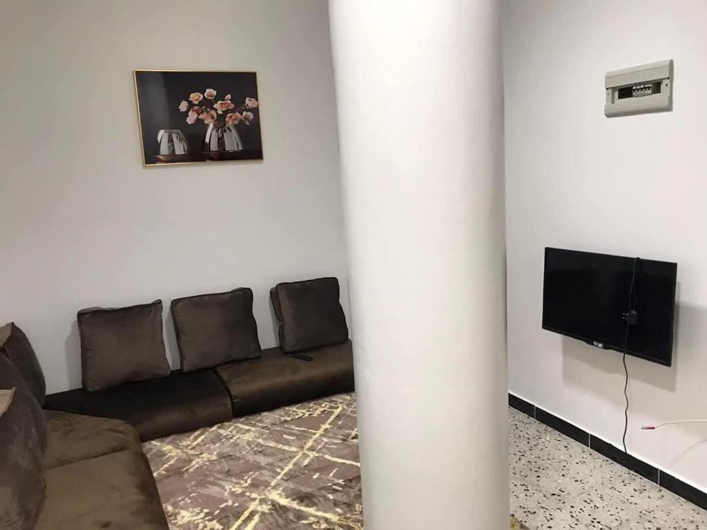 un salon avec un canapé et une télévision dans l'établissement رزق هاوس, à Ash Shūnah ash Shamālīyah