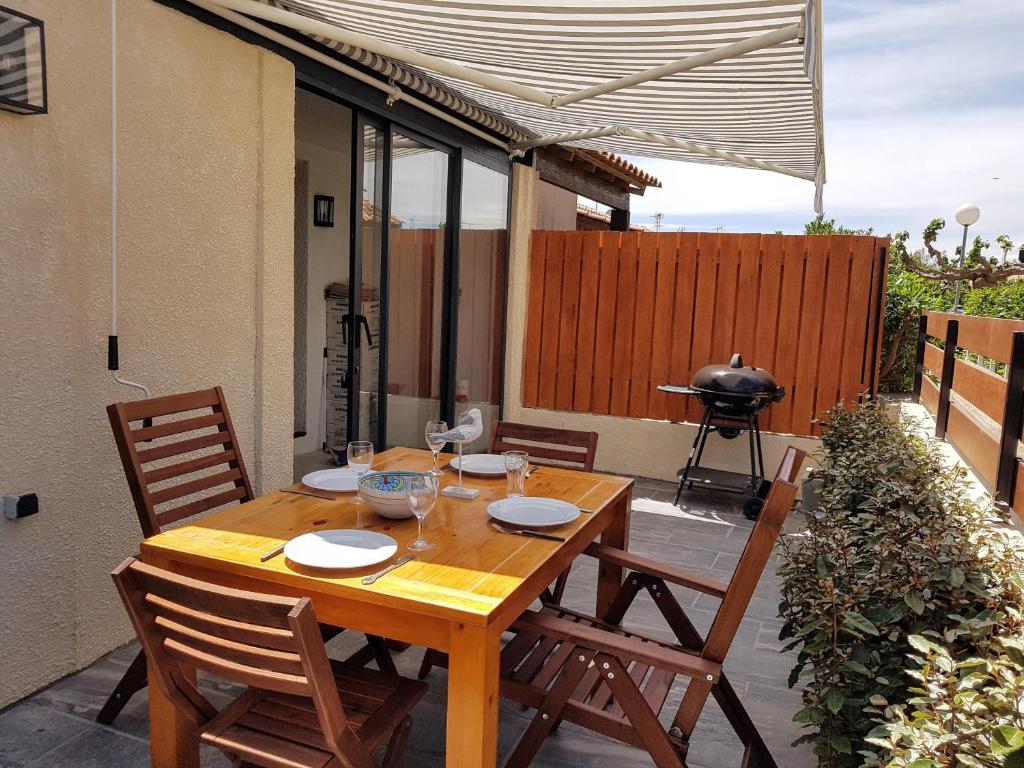 - une table et des chaises en bois sur une terrasse avec barbecue dans l'établissement Gruissan Ayguades maison de vacances L'Etang 4 personnes, à Gruissan