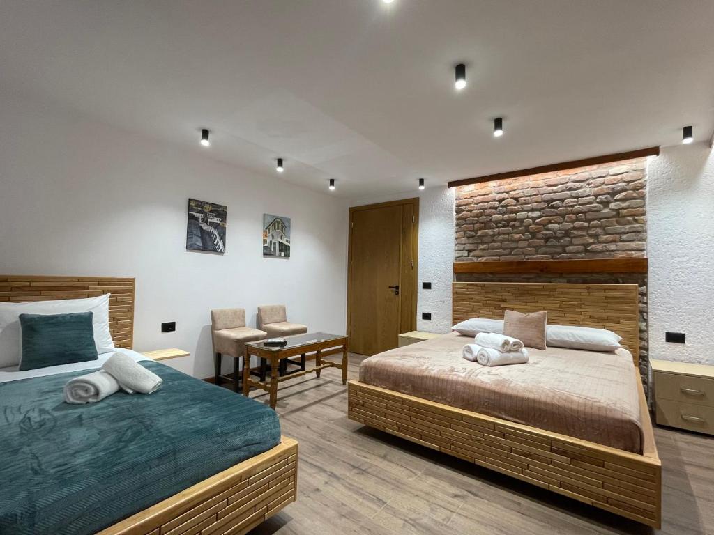 a bedroom with two beds and a brick wall at Villa Çabeli in Gjirokastër