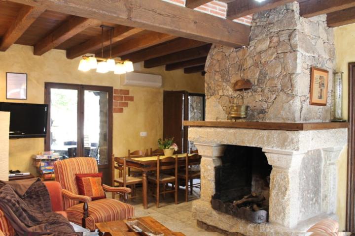 a living room with a stone fireplace and a dining room at Las cabachuelas casas rurales in San Miguel de Valero
