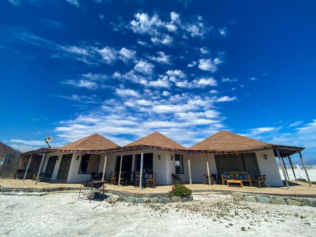 a house with a roof on the beach at Casona TikiTano Lodge 12 personas in Totoralillo