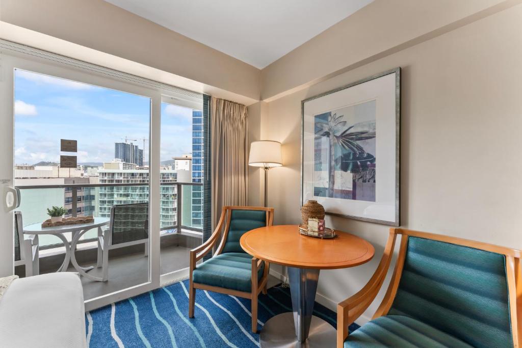 ホノルルにあるAla Moana Hotel Condo 15th floorのテーブルと椅子、窓が備わるホテルルームです。