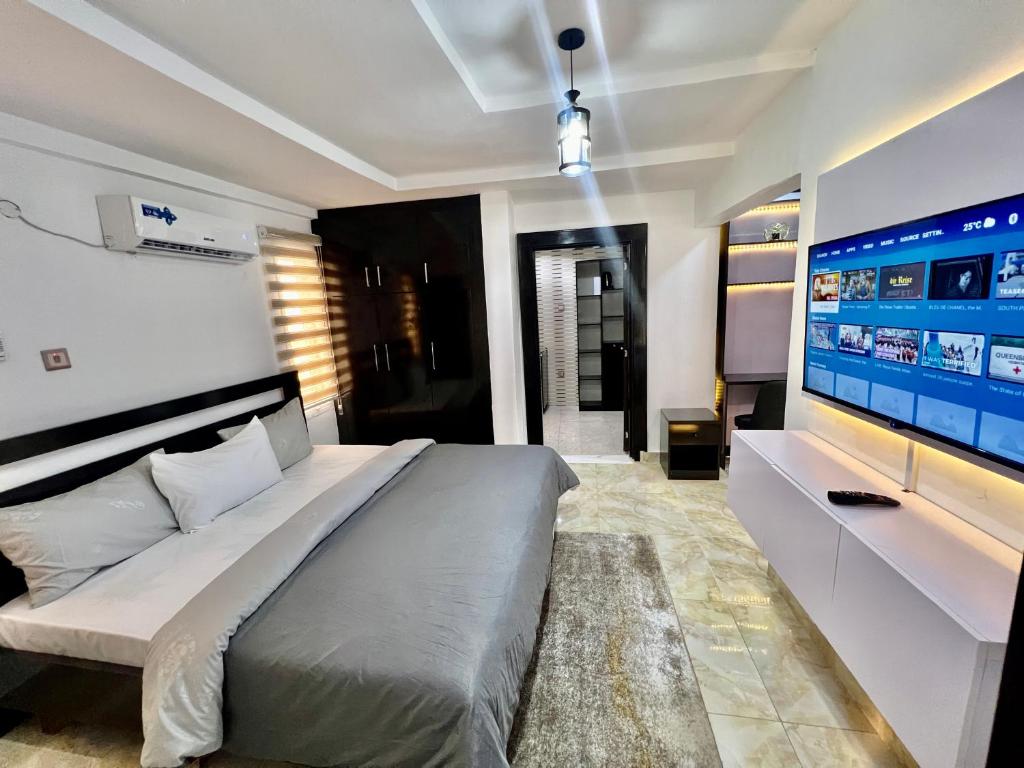 a bedroom with a large bed and a flat screen tv at Konar-Apts, Cozy Room with private kitchen, City view Balcony, 24hrs power, Security, Wifi, Gwarinpa Express by Dawaki Junction in Gwarinpa