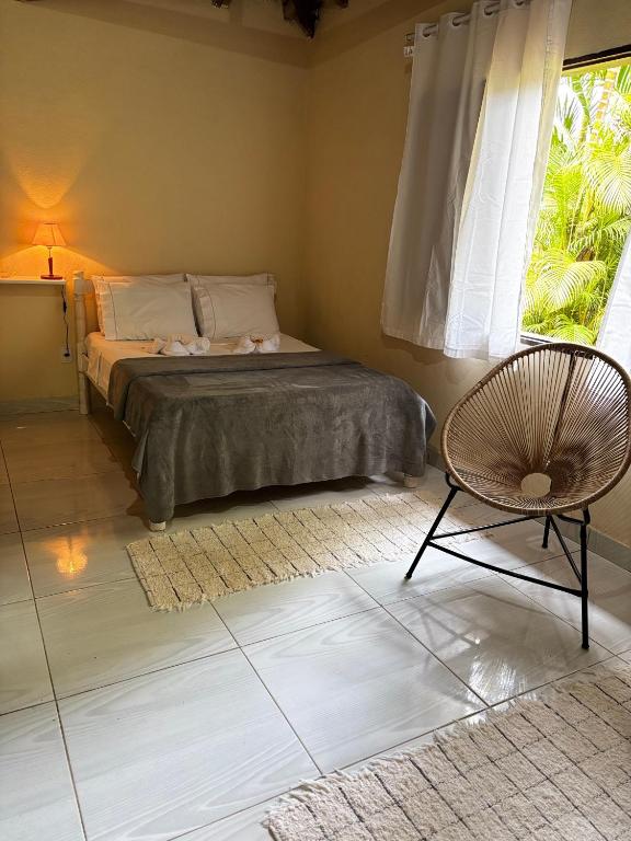 a bedroom with a bed and a chair and a window at Chalé Canoa in Paraty