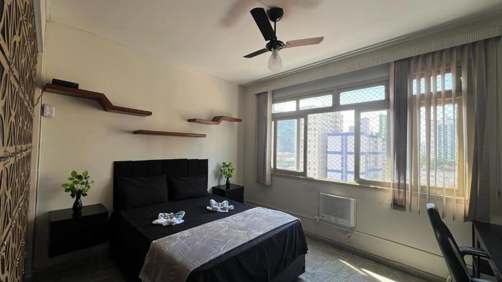 a bedroom with a bed and a ceiling fan at Kitnet completa com ar condicionado in São Vicente