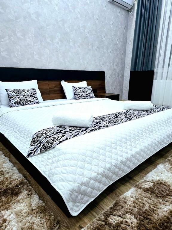 a large bed with white sheets and pillows at Golden house deluxe in Bukhara