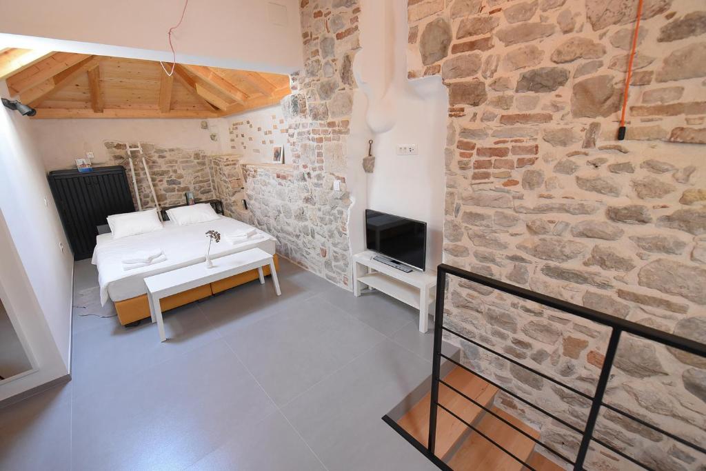 a bedroom with a bed and a stone wall at Pylon Rooms in Split