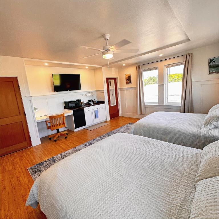 a bedroom with two beds and a television in it at Hilo Town Inn in Hilo