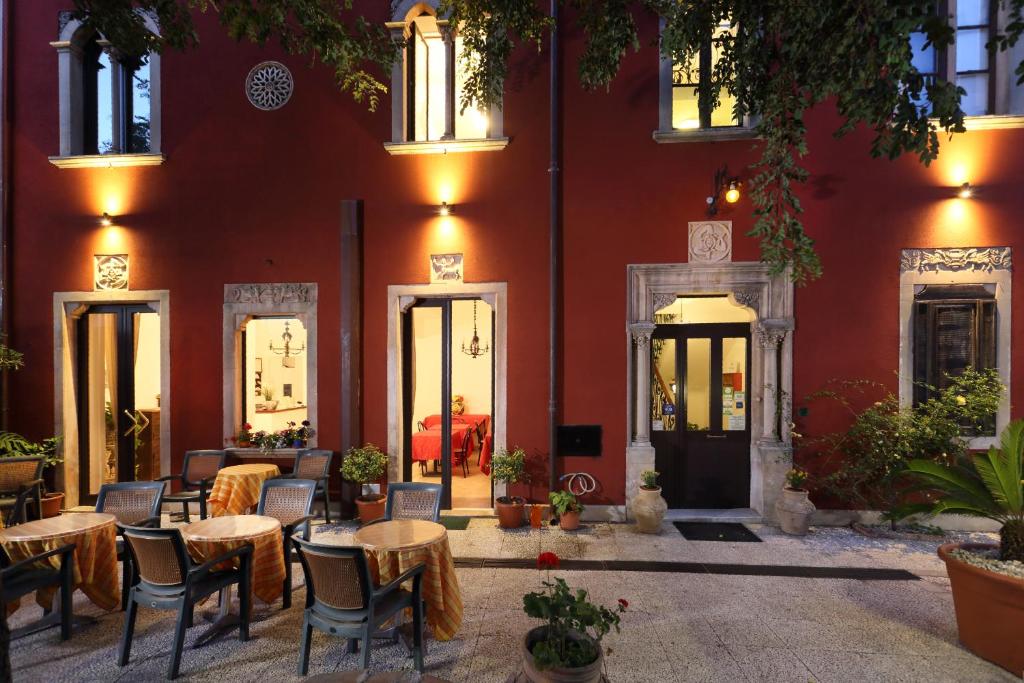 a restaurant with tables and chairs in front of a red building at Villa Astoria in Taormina