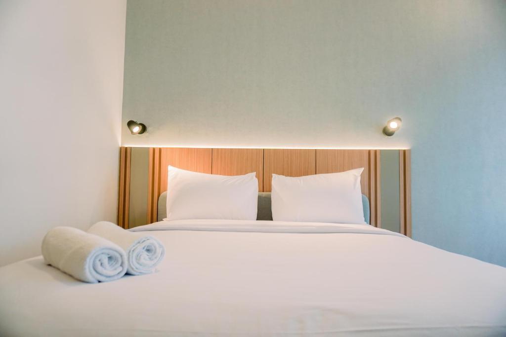 a white bed with two towels on top of it at Stunning Studio Transpark Bintaro Apartment By Travelio in Tangerang