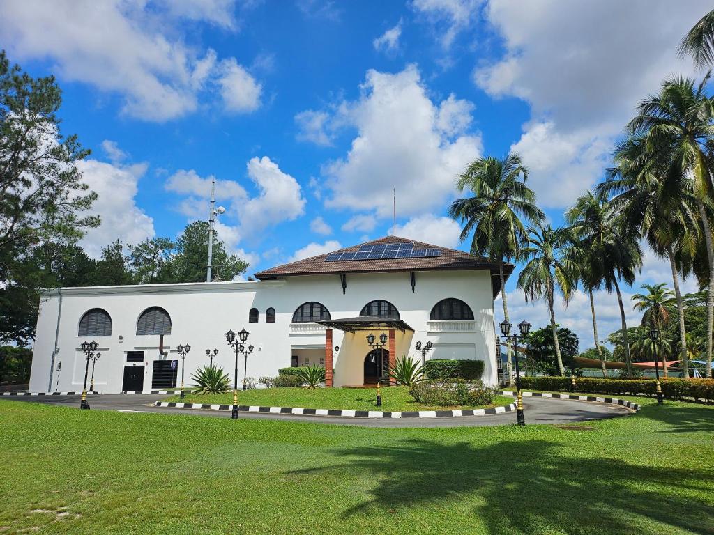 ein weißes Gebäude mit Palmen davor in der Unterkunft Ponderosa Golf & Country Resort in Johor Bahru