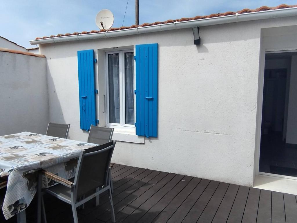 une table et des chaises sur une terrasse avec volets bleus dans l'établissement Maison de Charme à Domino, Oléron - Idéale pour Familles et Amis, 4 Pers, Proche Plages et Marché - FR-1-778-27, à Saint-Georges-dʼOléron