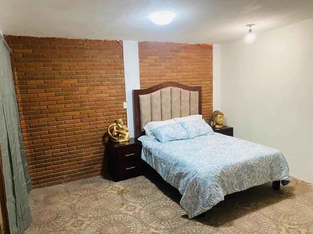 a bedroom with a bed and a brick wall at Cabaña rodeada de naturaleza in Pátzcuaro