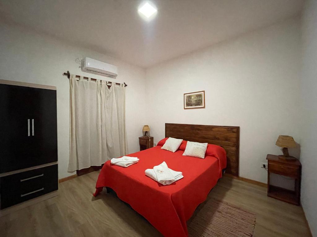 Departamento Cafayate في كفايات: غرفة نوم بسرير احمر مع بطانية حمراء