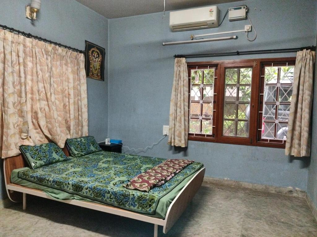 a bedroom with a bed in a room with windows at Metropolitan Retreat in Bengaluru